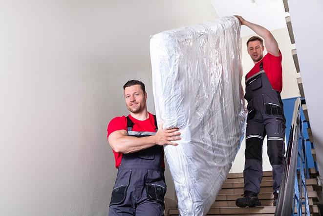 team carrying a large box spring out of a bedroom in Bellevue